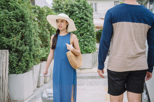 穿着蓝色连衣裙戴着帽子走在商业街上的美丽的亚洲女游客。