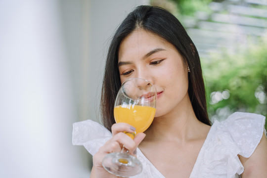 美丽的亚泰美女特写黑色长发白衬衫喜欢喝健康的橙汁