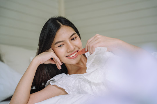 年轻的亚洲泰国女人的长头发，在卧室里涂上唇膏。