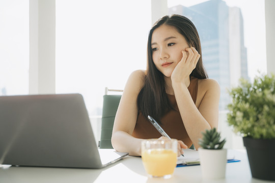 美丽的亚泰女商人在办公楼的笔记本电脑上工作。