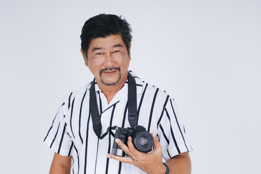 穿着白衬衫的亚洲成年男子，在白色背景上用相机拍摄。