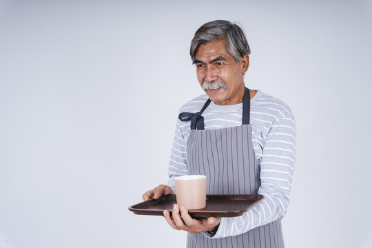 在白色背景上，老服务生拿着咖啡杯和托盘的肖像。