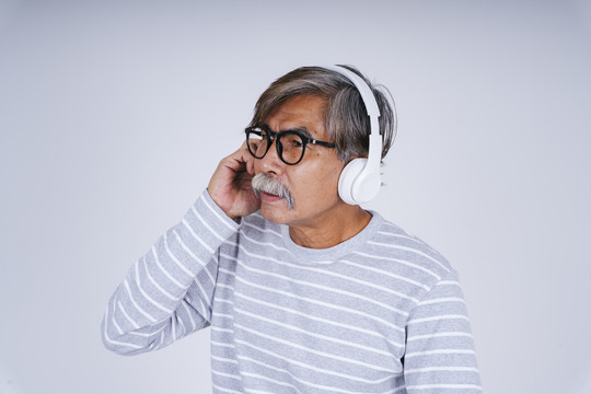 老人的肖像，戴着耳机在白色背景上听音乐。