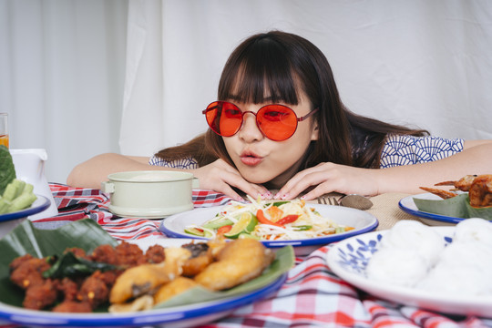 一位戴着红色眼镜的亚洲年轻女子在桌上看着伊桑的食物。