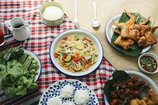 顶视图-餐桌上的一套伊桑美食，包括木瓜沙拉、烤鸡、米粉、辛辣肉末和蔬菜。