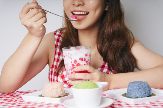 亚洲年轻女子用勺子吃菱角甜点。