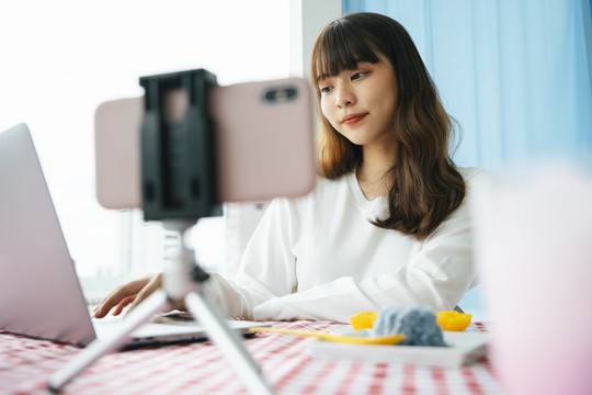 年轻的亚洲黑发女子在社交媒体平台上现场准备食物。