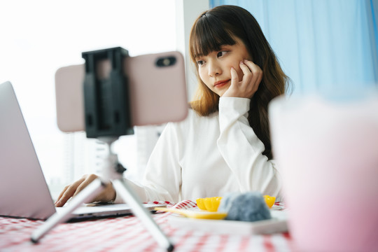 年轻的亚洲黑发女子在社交媒体平台上现场准备食物。