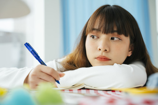 亚洲黑发女子在家写书的特写写真。