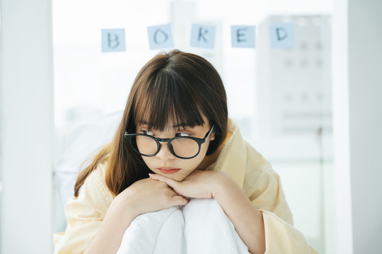 可爱的年轻亚洲黑发女子戴着眼镜躺在床上。无聊的女孩在沙发上放松。