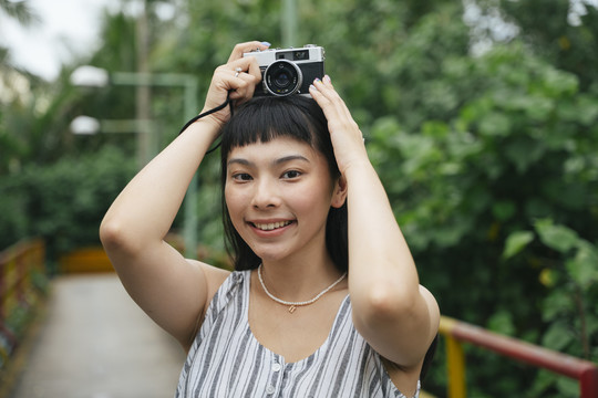 用老式相机拍摄亚洲年轻女性的时尚肖像。度假胜地的美丽摄影师。