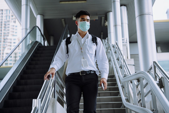 亚洲商务人士戴着面具走下城市的楼梯。