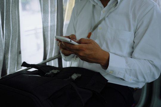 商务人士在公共汽车内使用智能手机的特写手。