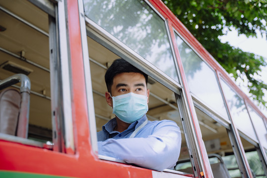 坐在公共汽车窗边的亚洲商人。在曼谷乘公共汽车旅行。