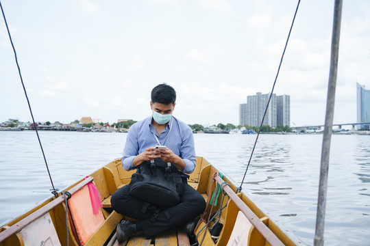 亚洲商人戴着面具在曼谷乘船旅行。