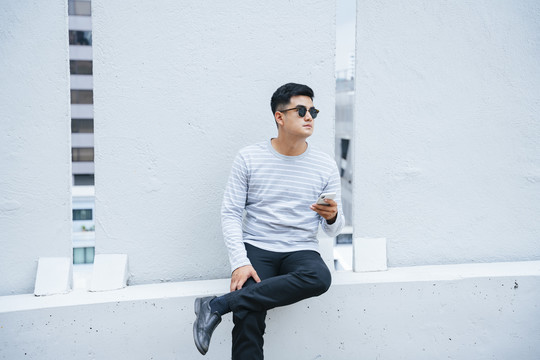 时尚亚洲成年男子在户外街头戴墨镜的写真。