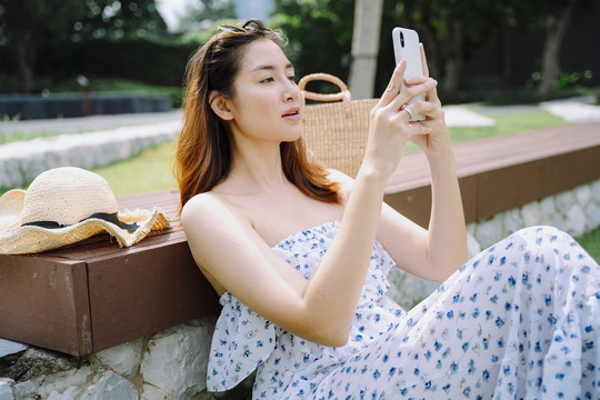 美丽的亚洲女游客在公园户外使用智能手机。