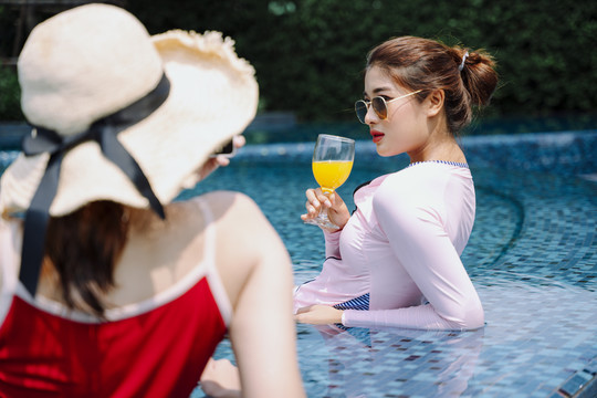 美丽的亚洲女游客喜欢用智能手机在游泳池拍照。