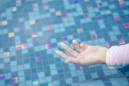 女士用手触摸游泳池表面。