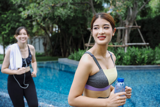 美丽健康的女运动员一起在游泳池附近跑步。