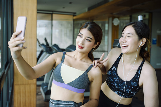 美丽健康的女人穿着运动内衣在健身房用智能手机自拍。