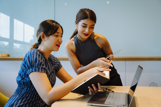 两位亚洲女商人一起看笔记本电脑。