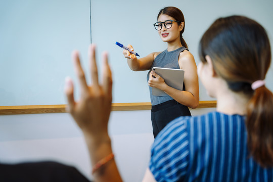 亚洲女商人在会议上征求意见。人们举手提问。