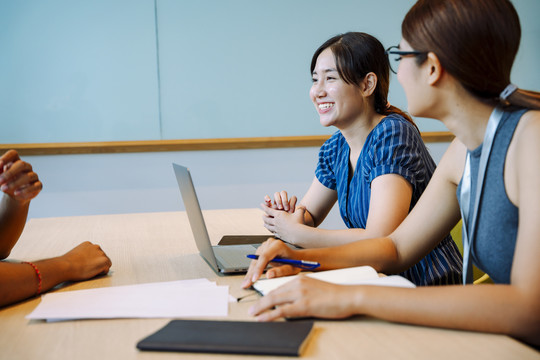 侧视图-两位亚洲女商务人士在会议室与客户交谈。
