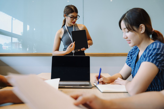 亚洲女商务人士在会议室用数字笔记本电脑讲解战略计划。