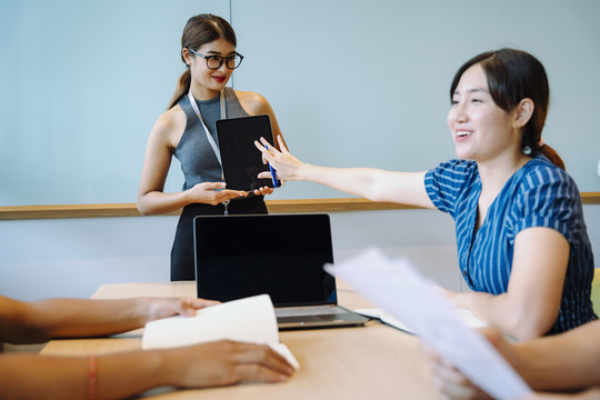 亚洲女商务人士在会议室用数字笔记本电脑讲解战略计划。