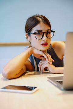 亚洲女商人戴着眼镜坐在笔记本电脑前。