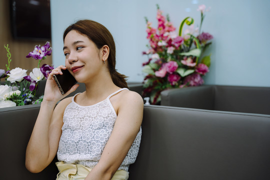 一位亚洲女性在进入美容诊所前，通过智能手机向她的朋友寻求建议。