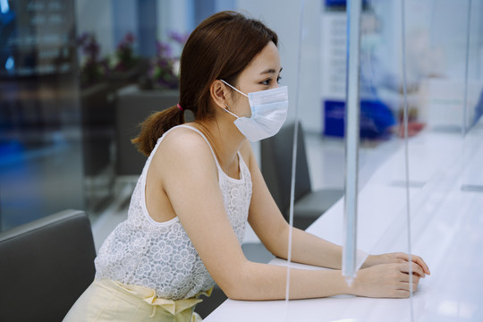 美丽的亚洲年轻女子戴着面具和美容诊所的工作人员交谈。