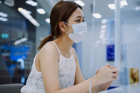 美丽的亚洲年轻女子戴着面具和美容诊所的工作人员交谈。