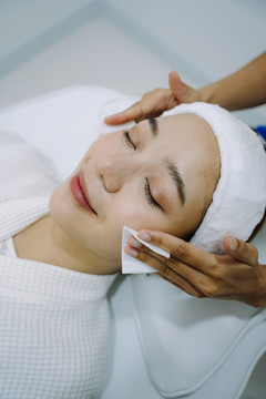美容师在美容诊所和水疗中心用化妆棉洗脸。