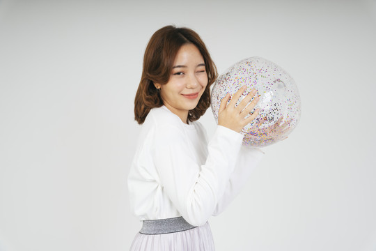 美丽的亚洲年轻女子，白色背景上有闪闪发光的塑料球。