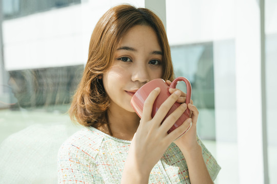 美丽的亚洲女人在办公室喝咖啡的画像。