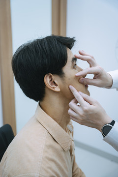 美容师在美容诊所检查年轻人的面部进行面部治疗。
