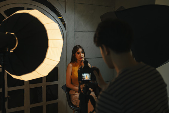 年轻的亚洲摄影师和模特在暗室摄影棚拍摄。