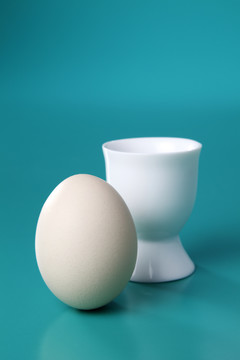 蓝色背景的鸡蛋，背面有蛋杯。