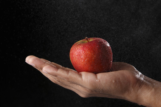 手掌上有水滴的苹果。