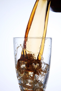 把可乐饮料倒进加冰的玻璃杯里