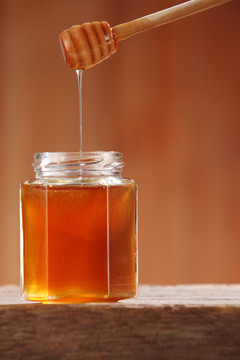 木制背景上的蜂蜜罐
