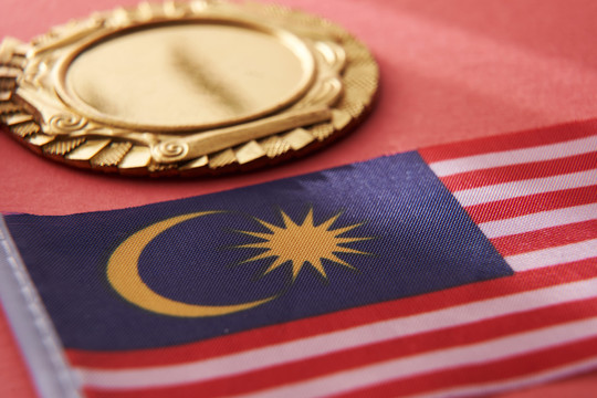 红色背景上的金牌和马来西亚国旗特写