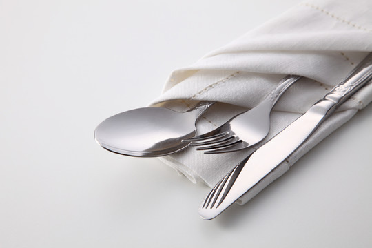 白色背景的折叠餐巾，带叉子、勺子和刀