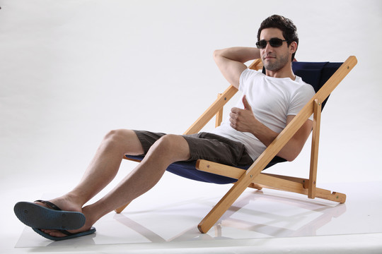 戴着太阳镜的男人大拇指朝上躺在躺椅上