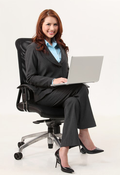 坐在办公椅上拿着笔记本电脑的女商人