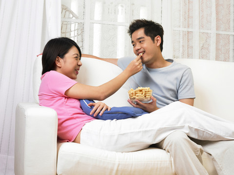 女人从她丈夫拿着的碗里拿出一勺零食