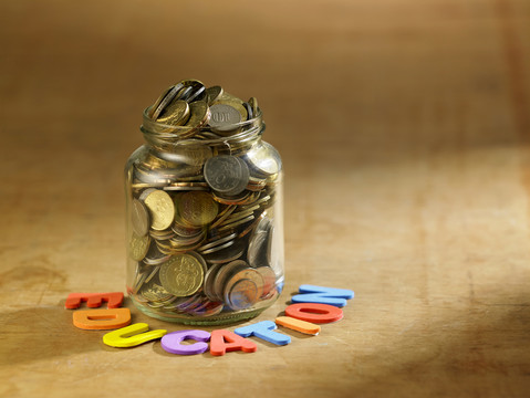 把装满硬币的罐子放在木桌上