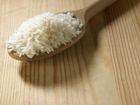 木桌上盛满米饭的勺子
